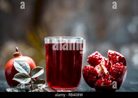 Organische Wesen der Granatapfel mit rohen Granatapfel auf Holz- Oberfläche in einem transparentem Glas. Stockfoto