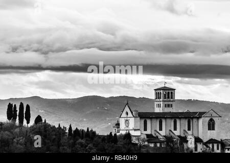 Schöne Sicht auf die St. Franziskus Kirche in Assisi (Umbrien, Italien) von einem ungewöhnlichen Ort, mit Moody Wolken im Himmel Stockfoto