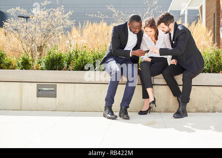 Business Team liest eine SMS-Nachricht auf dem Smartphone, aufmerksam und begeistert Stockfoto