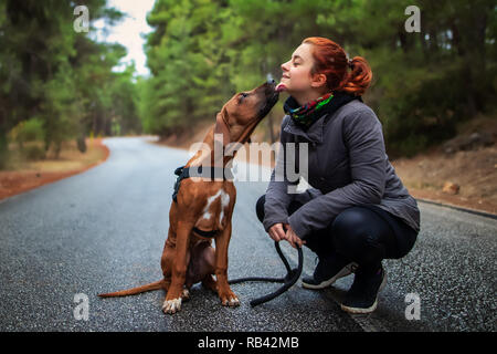 Portrait von Happy Jugendmädchen und Rhodesian Ridgeback Hund. Hund, girl Sweet Kiss lecken. Liebe Tiere liebe mein Haustier Stockfoto