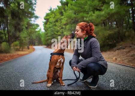 Portrait von Happy Jugendmädchen und Rhodesian Ridgeback Hund. Hund, girl Sweet Kiss lecken. Liebe Tiere liebe mein Haustier Stockfoto