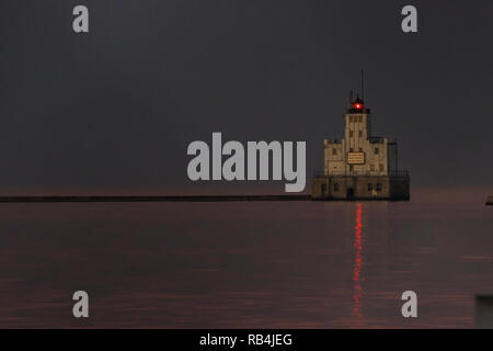 Milwaukee breakwater Leuchtturm in Milwaukee bay blinkt ein rotes Licht als Finsternis über Michigan See in Wisconsin fällt. Stockfoto