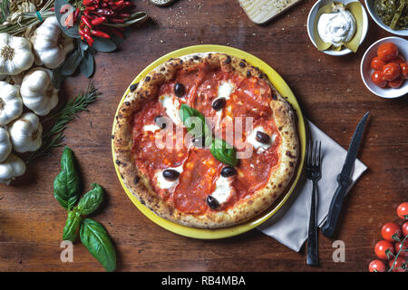 Ansicht von oben Hintergrund italienische neapolitanische Pizza mit Salami, Salami, schwarze Oliven, Käse und Basilikum auf Rahmen Zusammensetzung Stockfoto