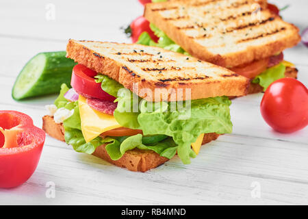 Zwei Sandwiches mit Schinken, Salat und frisches Gemüse auf weißem Hintergrund Stockfoto