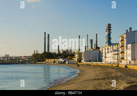 Strand und Wohngegend in San Roque, mit Cepsa Raffinerie Algeciras, hinter, Andalusien, Spanien. Stockfoto