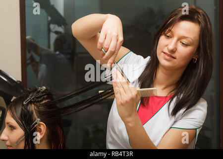 Friseur schneiden dunkle Haare mit professioneller Schere, die Pflege von Split Haar endet. Stockfoto