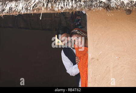 Portrait von Happy indischen Ehepaar in traditioneller Kleidung peeking aus Haus im Dorf Stockfoto