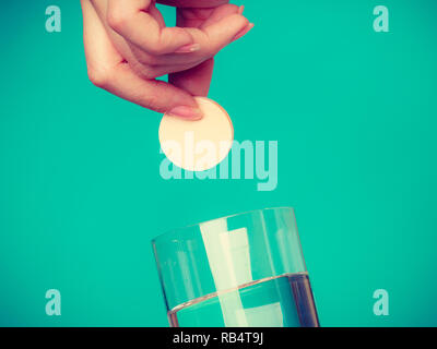 Vitamine, Gesundheit, Medikamente. Person werfen Vitamin Mineral ergänzen Brausetablette in einem Glas Wasser. Studio gedreht auf blauem Hintergrund Stockfoto