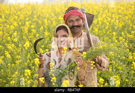 Ländlichen Indischen paar Ernte von Raps mit Sichel und Hacke in der Agrarwirtschaft Stockfoto
