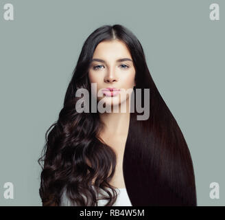 Schöne Mode Modell Frau mit langen, geraden Haaren und perfekte curly Frisur auf blauem Hintergrund Stockfoto