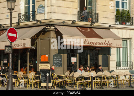 Man saß Kaffee trinken außerhalb Pariser Restaurant "esmerelda" neben der Notre Dame Kathedrale, in der Frühlingssonne mit einer Frau auf dem Balkon oben. Stockfoto