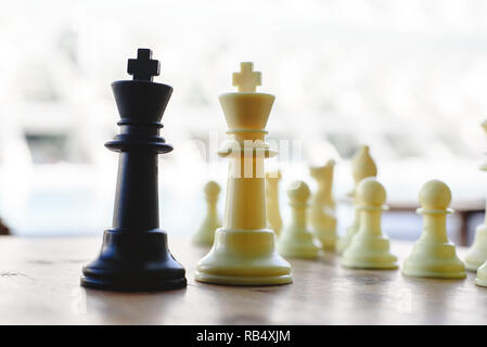 Schwarz und Weiß schach Könige zwischen defokussierten Stücke auf Holzbrett konfrontiert. Stockfoto