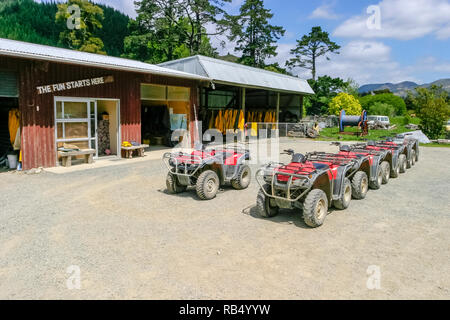 Red Quad Bikes aufgereiht außerhalb von Gebäuden im Cable Bay Adventure Park, in der Nähe von Hira, Nelson, Südinsel, Neuseeland. Stockfoto