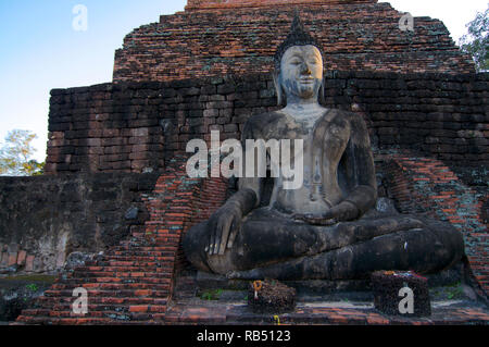 Schöne sitzender Buddha Statue vor einem alten Ziegel Chedi in der Sukhothai Historical Park, Thailand Stockfoto