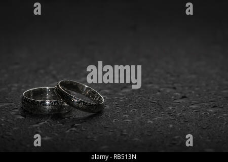 Silberne Hochzeit Ringe auf einem Rock Hintergrund mit Wassertropfen Stockfoto