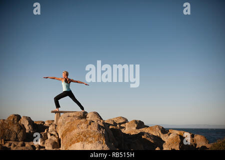 Frau Yoga auf den Felsen am Strand. Stockfoto