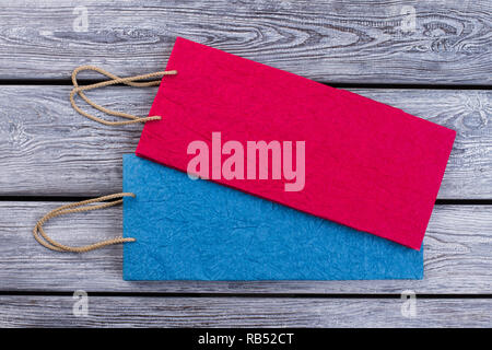 Bunte Tüten liegen auf Holz- Hintergrund. Rosa und Blaue Säcke aus Papier. Geschenke Verpackung Konzept. Stockfoto