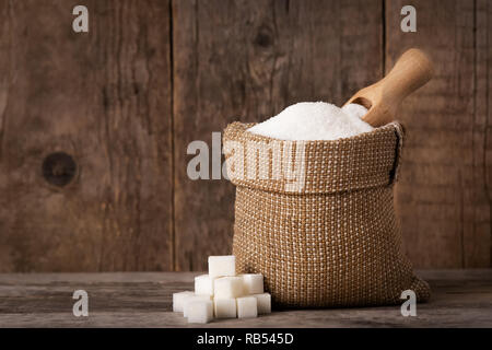 Weißzucker in sackleinen Tasche und Schaufel auf Holz- Hintergrund Stockfoto