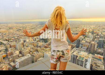 Blick auf die Skyline von Los Angeles in Kalifornien, USA. Reise und Tourismus amerikanische Konzept. Blond touristische Frau an die Innenstadt von LA Stadtbild Blick von der Aussichtsplattform. Sonnenuntergang geschossen.