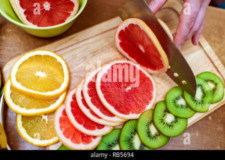 Hände Hausfrauen Frauen mit einem Messer frische Grapefruit auf dem Schneidebrett der Küchentisch Schnitt Stockfoto