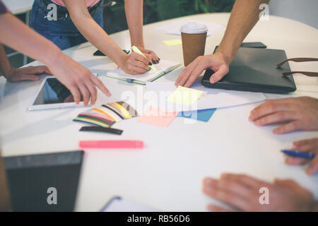 Bild von Männern und Frauen die Hände zeigen auf bunten Aufkleber und ein Stück Papier. Sie arbeiten zusammen. Stockfoto