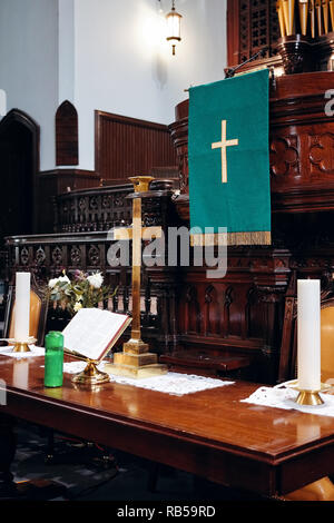 Innenraum der evangelischen Kirche Altar mit goldenem Kreuz, Bibel und Kerzen auf. Stockfoto