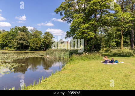 Ein junges Paar beim Picknick am See bei Stowe House Gardens, Buckinghamshire UK Stockfoto