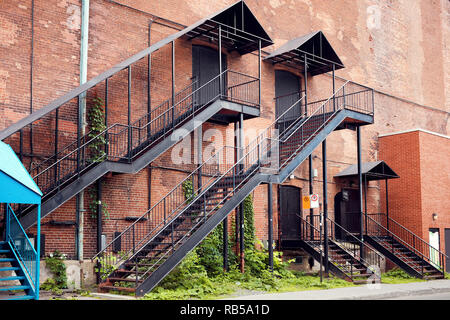 Alten roten Ziegeln industrielle Gebäude Fassade mit schwarzem Eisen äußeren Leiter Treppe. Stockfoto