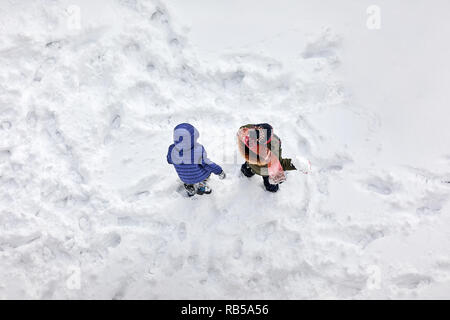 Antenne oben Blick auf zwei kleine Kinder spielen im Schnee Stockfoto