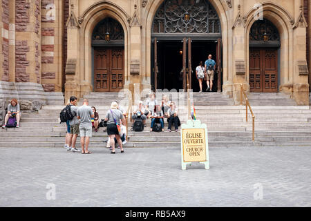 Gruppe von Menschen sitzen vor St. James Vereinigte Protestantische Kirche hinter Kirche öffnen sich mit einem Lgbt Regenbogen Flagge Stockfoto