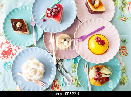 Leckere kleine Kuchen und Torten auf bunten Platten Stockfoto