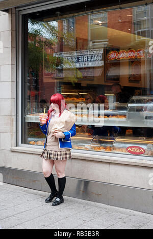 Jungen asiatischen Teenager Schulmädchen tragen Schuluniform hält einen Smoothie in die Hand und steht vor dem Schaufenster eines Store Stockfoto