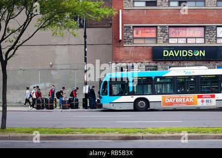 Jungen asiatischen Menschen, die in der Warteschlange warten, mit ihrem Gepäck auf dem Bus in Montreal, Quebec, Kanada zu erhalten. Stockfoto