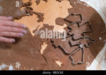Junge Frau, die Lebkuchen Kekse für Weihnachten. Teig und Backen Ausstechformen auf einem Holztisch. Stockfoto
