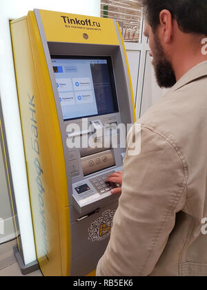 Samara, Russland - 26. AUGUST 2018: Bartgeier im mittleren Alter Geschäftsmann kaukasischen Aussehen verwendet eine Kreditkarte am Geldautomaten Bank Tinkoff. Stockfoto