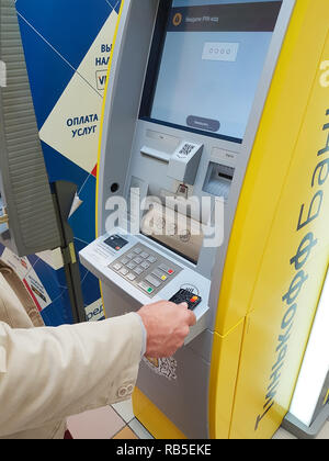 Samara, Russland - 26. AUGUST 2018: Bartgeier im mittleren Alter Geschäftsmann kaukasischen Aussehen verwendet eine Kreditkarte am Geldautomaten Bank Tinkoff. Stockfoto