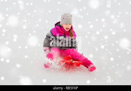 Gerne kleine Mädchen Rutschen auf Schlitten im Winter Stockfoto