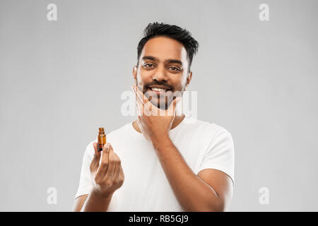 Lächelnd inder Anwendung Pflege Öl zu Bart Stockfoto