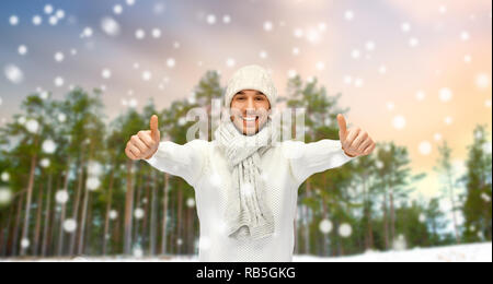 Lächelnder Mann mit Daumen hoch über Winter Forest Stockfoto