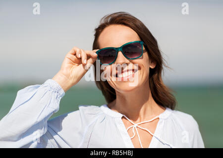 Glücklich lächelnde Frau mit Sonnenbrille auf Sommer Strand Stockfoto