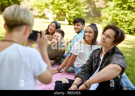 Freunde fotografieren im Sommer Picknick im Park Stockfoto