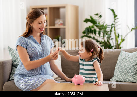 Schwangere Mutter und Tochter mit Sparschwein Stockfoto