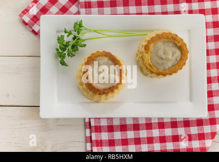 Blätterteig vol-au-vents gefüllt mit pilzragout an einem hölzernen Tisch Stockfoto