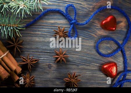 Weihnachten layout Konzept auf Holzuntergrund mit Zimt und Anis Sterne Gewürze, blauem Faden und roten herzförmigen Bonbons Stockfoto