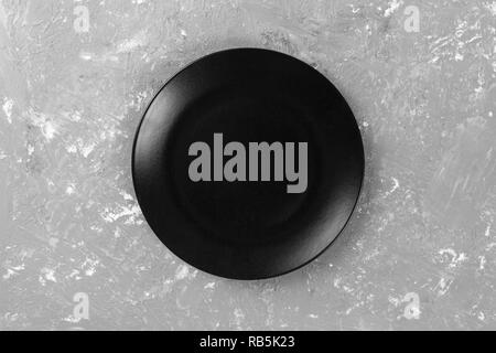 Blick von oben auf die Matte runde Leere schwarze Platte auf dunklen Zement Hintergrund Platz für Sie entwerfen. Stockfoto