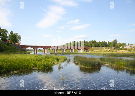 Schön, auf dem Land, Dorf, Blick auf die Altstadt, den alten roten Backstein Brücke über den kleinen Fluss namens Venta. In Lettland - Europa. Stockfoto