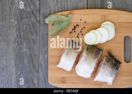 Stücke von Fisch auf einem Schneidebrett mit Gewürzen auf Holz rustikale vintage Hintergrund. Hintergrund, kopieren. Stockfoto