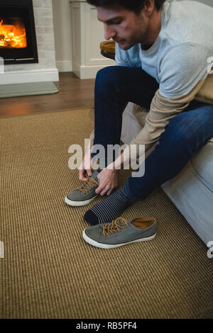 Mann binden Schnürsenkel in Wohnzimmer Stockfoto