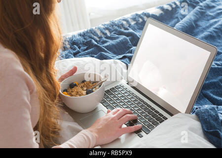 Frau mit Laptop beim Frühstück im Schlafzimmer Stockfoto