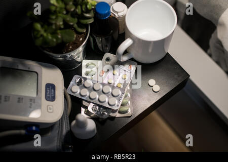 Themen Medizin Gesundheit und Pharma. Close-up Makro Blutdruck überwachen, eine Menge Blister mit Pillen auf dem Nachttisch im Schlafzimmer zu Hause Stockfoto